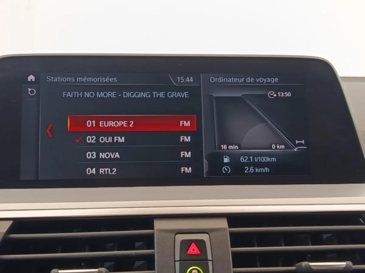 Écran central de navigation et radio d'une BMW X3 gris clair, affichant stations FM et ordinateur de bord.