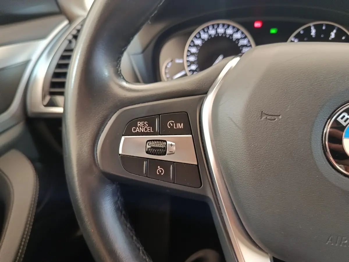 Gros plan sur le volant cuir et alu multifonctions du BMW X3 xDrive20d 2020, boutons de régulateur de vitesse visibles.