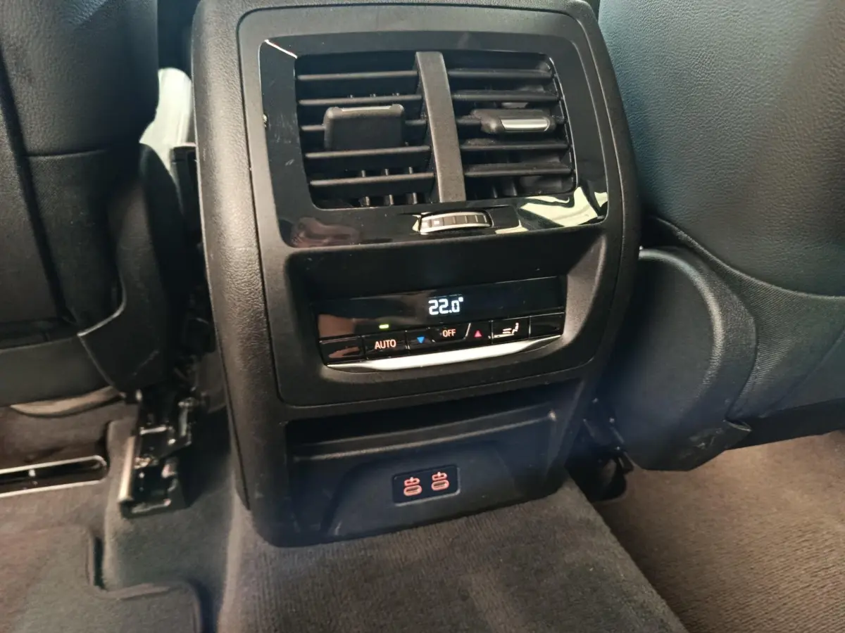 Vue rapprochée de la console arrière noire avec commandes climatisation et prises USB du BMW X3 gris clair 2020.