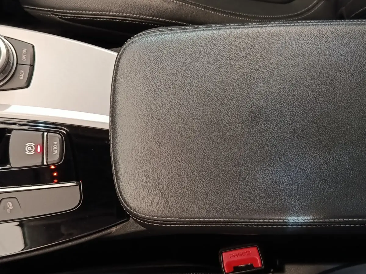 Gros plan sur la console centrale et accoudoir en cuir noir de la BMW X3 xDrive20d 2020, avec commandes électroniques visibles.