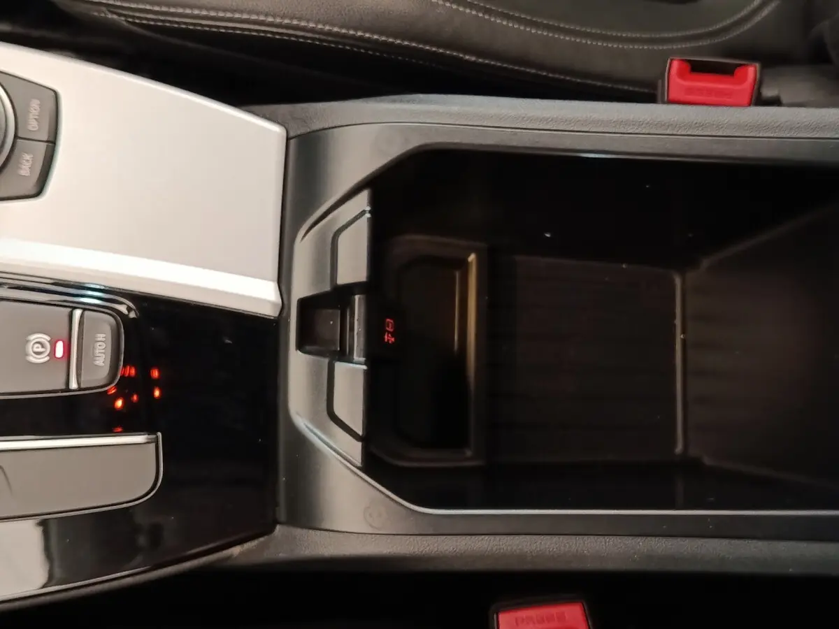Vue rapprochée de la console centrale noire de la BMW X3 xDrive20d 2020 avec bouton frein à main électrique et rangement ouvert.