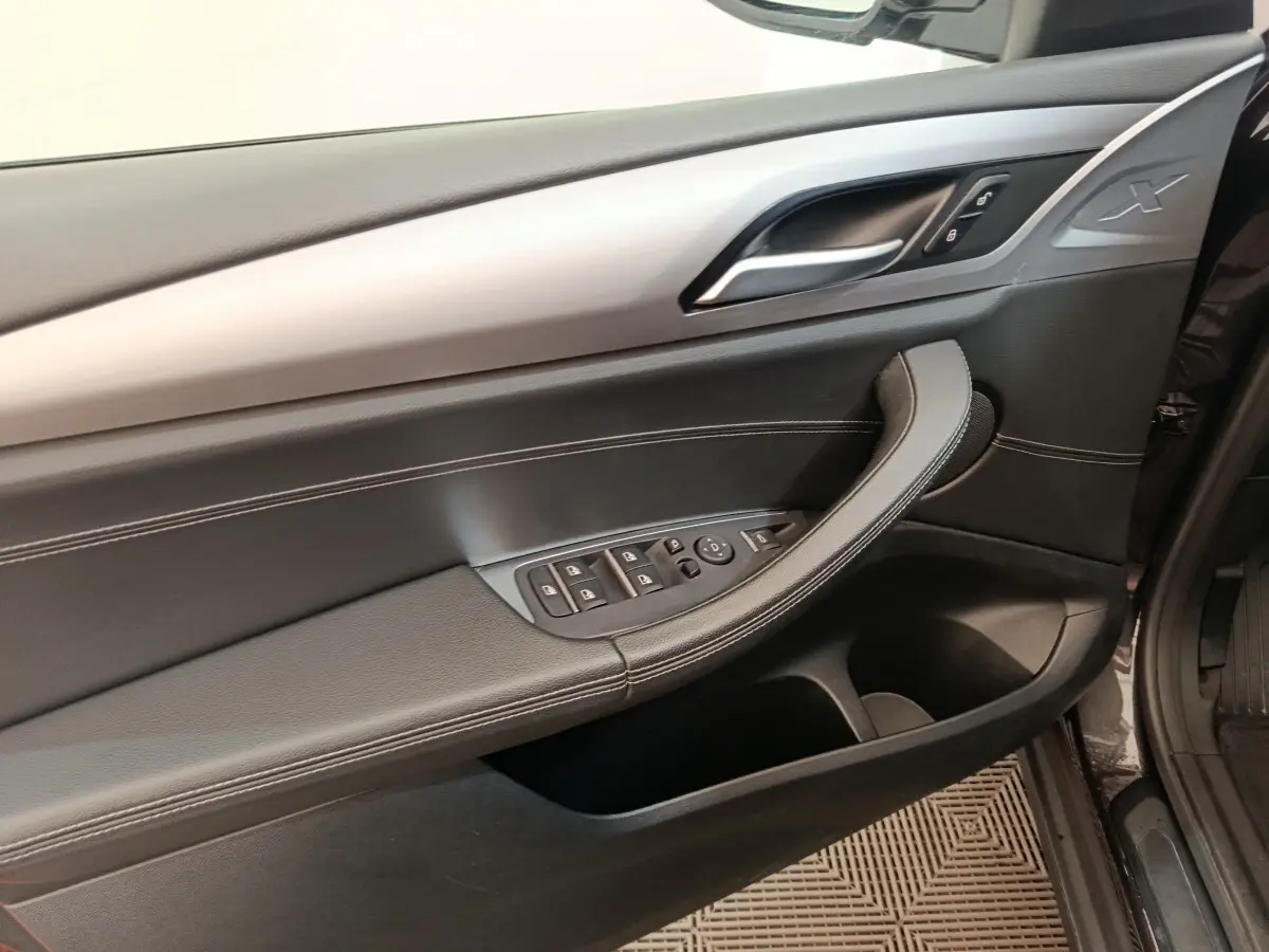 Vue rapprochée de la porte avant gauche de la BMW X3 gris clair, avec commandes vitres et insert alu.