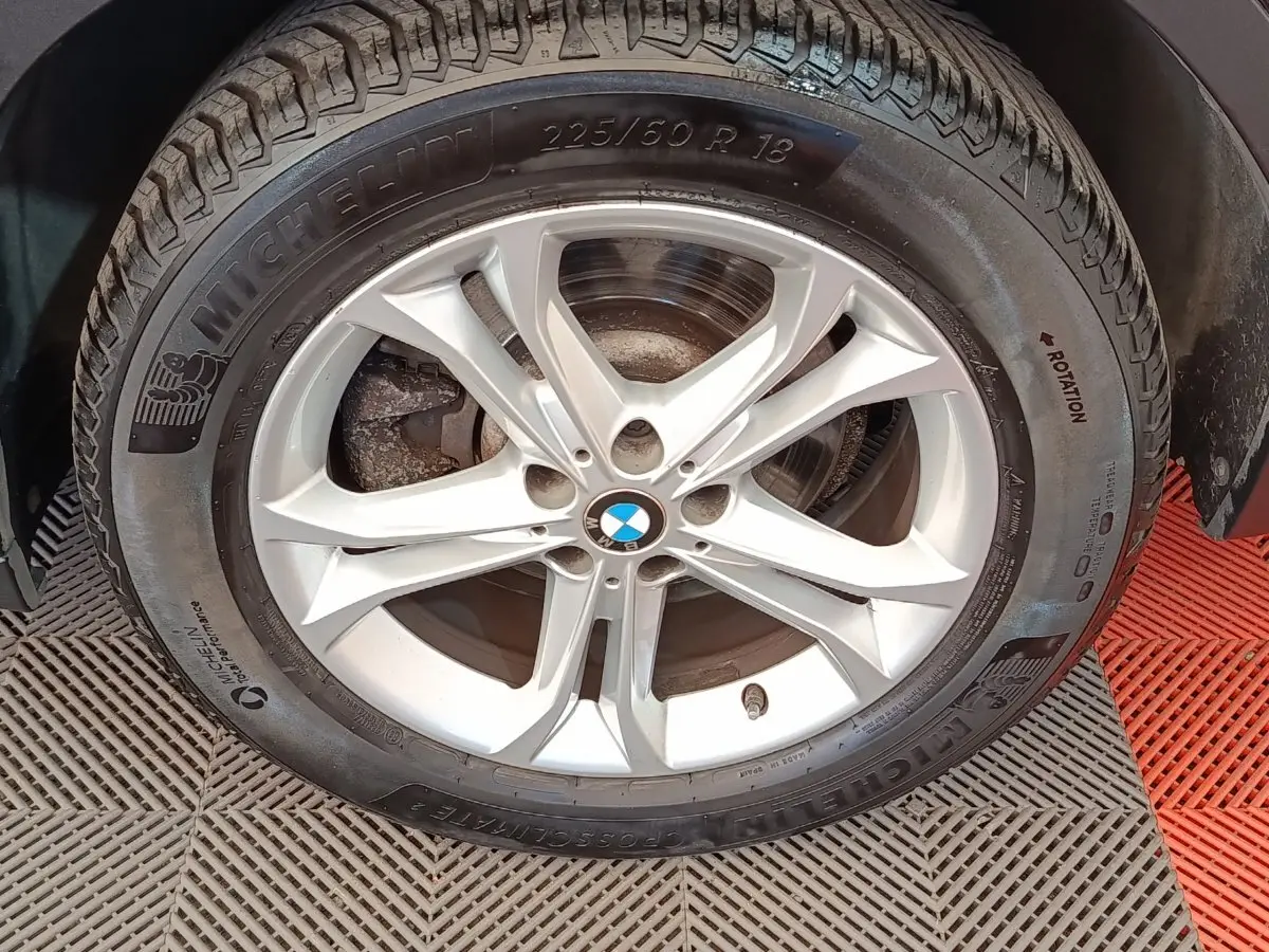 Gros plan sur la roue avant droite d’un BMW X3 gris clair, jante alliage 5 branches et pneu Michelin.
