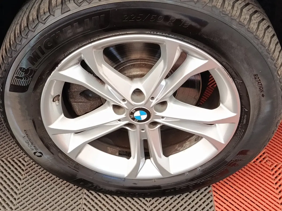 Gros plan sur la jante alu argentée avec logo BMW au centre et pneu Michelin noir.