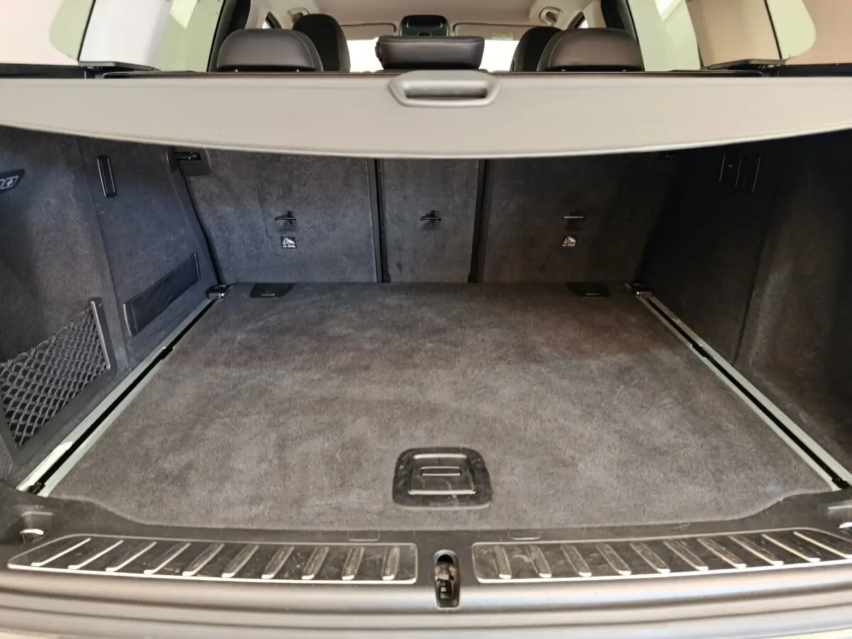 Coffre spacieux de BMW X3 gris clair vu de l'arrière avec banquette rabattable et filet de sécurité visible.