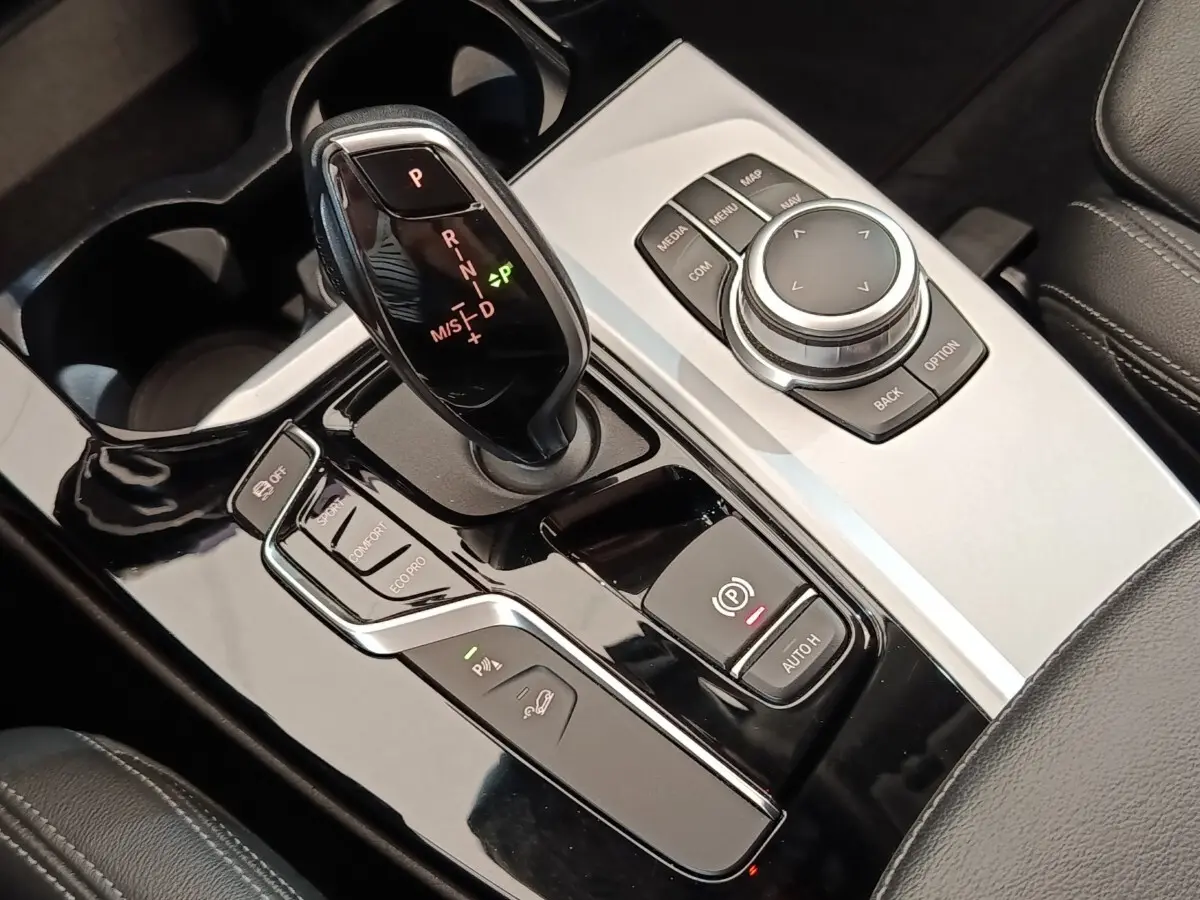Gros plan sur la console centrale noire et argentée avec levier de vitesse et commandes du BMW X3 gris clair 2020.