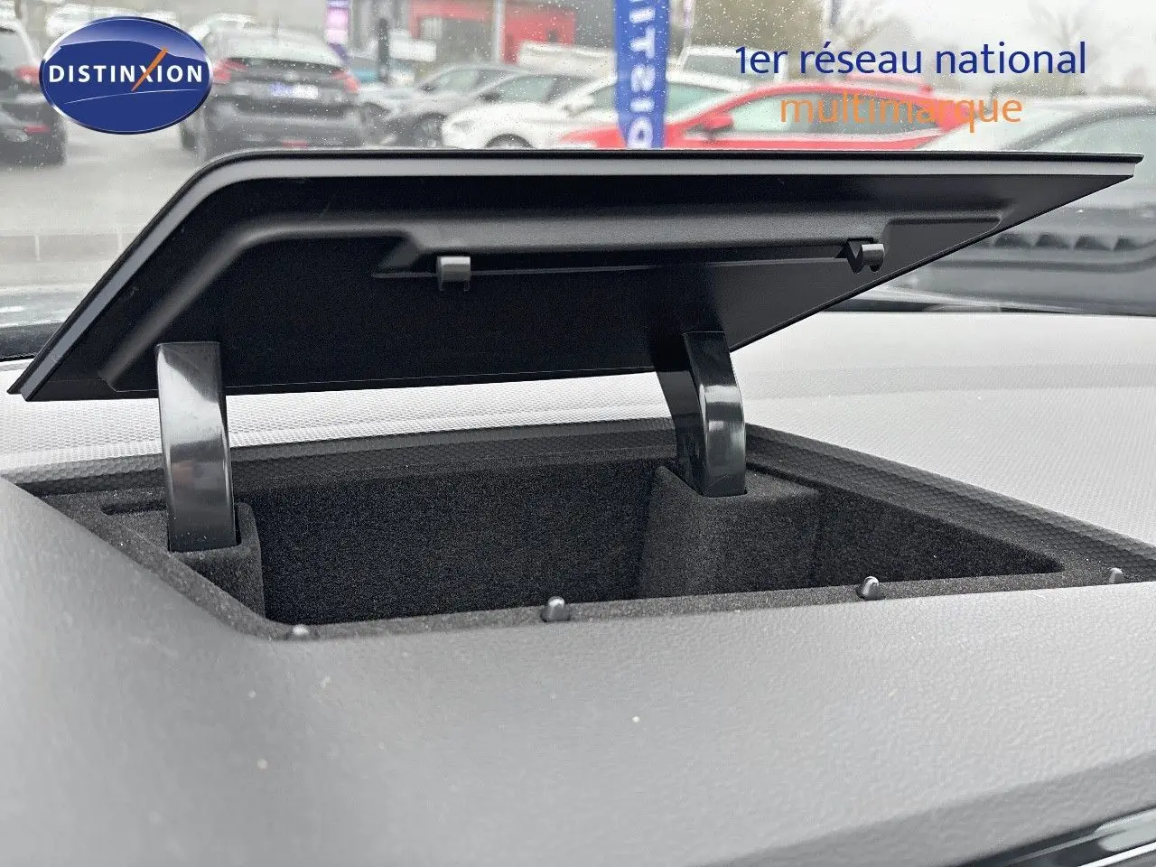 Coffre de rangement ouvert sur le tableau de bord du Volkswagen Tiguan 1.4 e-Hybrid gris lunaire, vue intérieure rapprochée.