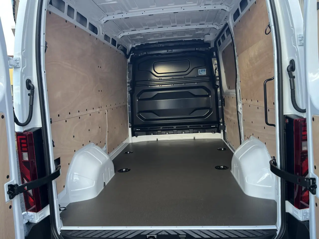 Vue arrière intérieure du Renault Master blanc 2025 montrant l'espace de chargement avec plancher bois et parois tôlées.