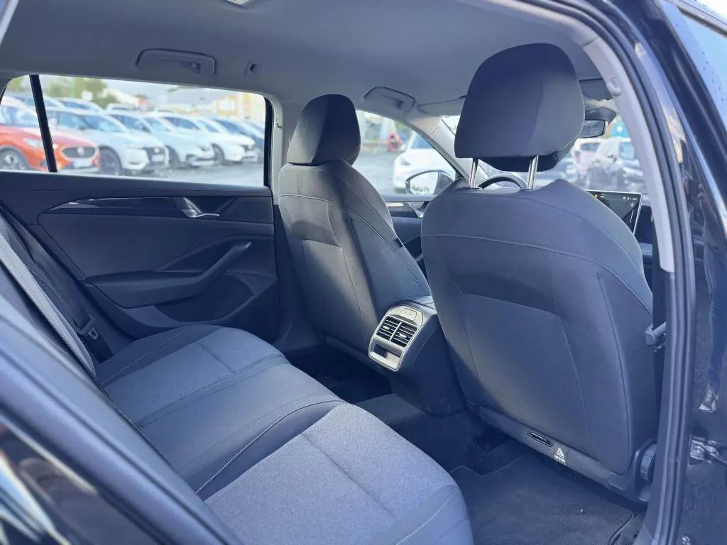 Vue intérieure arrière droite de la Volkswagen Passat SW noire 2024, montrant les sièges et la console centrale avec aérateurs.