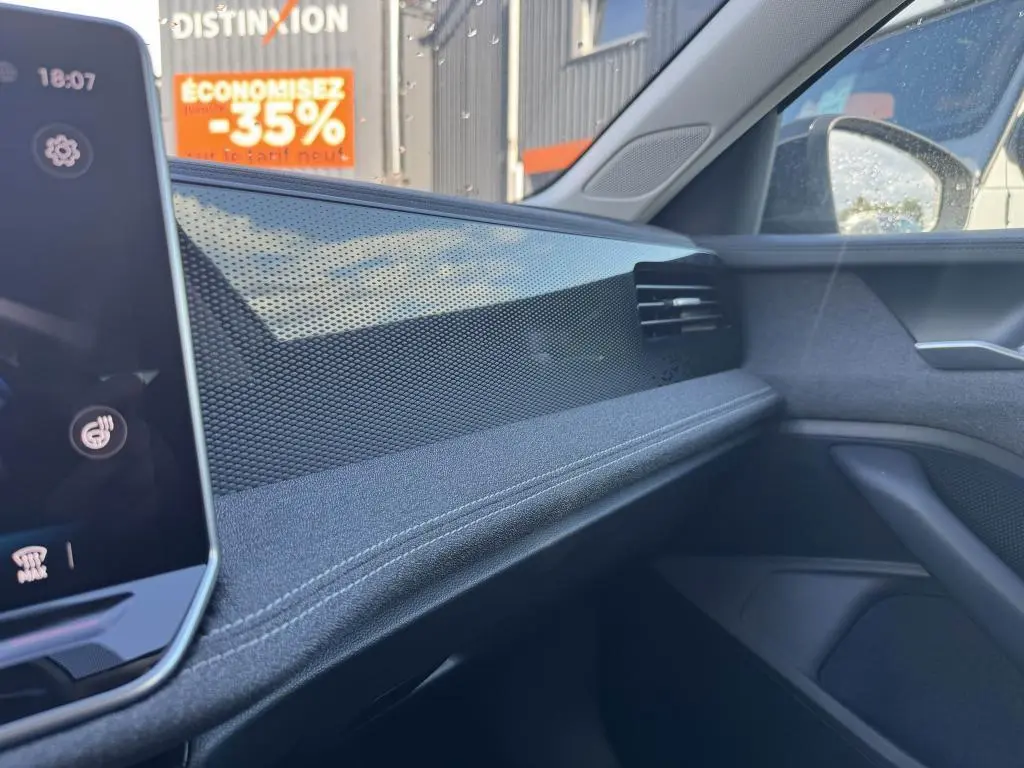 Détail de la planche de bord côté passager de la Volkswagen Passat SW noire 2024 avec finition tissu et inserts décoratifs brillants.