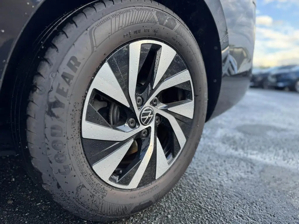 Gros plan sur la roue avant droite noire d'une Volkswagen Passat SW 2024 avec jante alliage bicolore et pneus Goodyear.