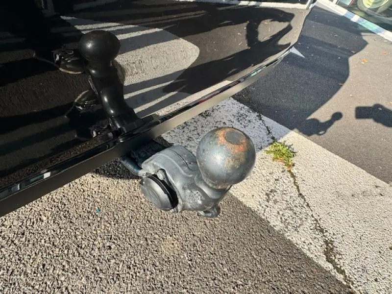 Gros plan sur l'attelage de remorque métallique d'une Volkswagen Passat SW gris manganèse métallisé, vue côté arrière droit.