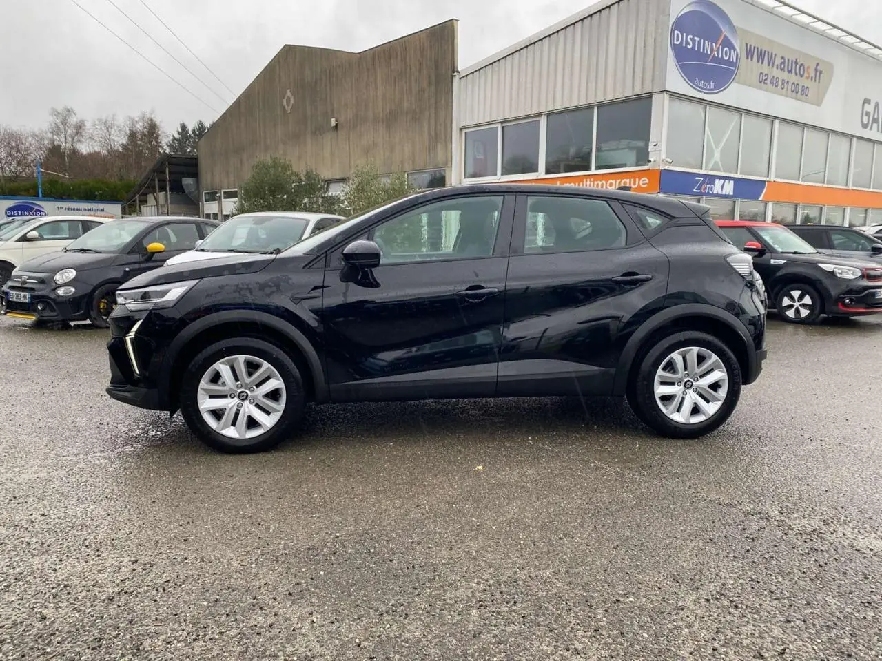 Profil côté gauche d'un Renault Captur noir étoilé 2025 garé devant un garage avec jantes argentées.