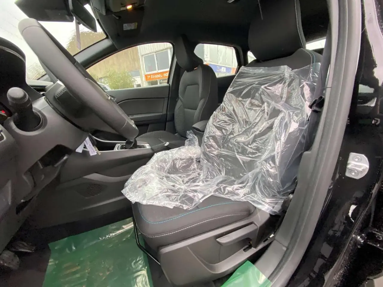 Vue intérieure côté conducteur du Renault Captur noir étoilé 2025, siège avant protégé par film plastique.