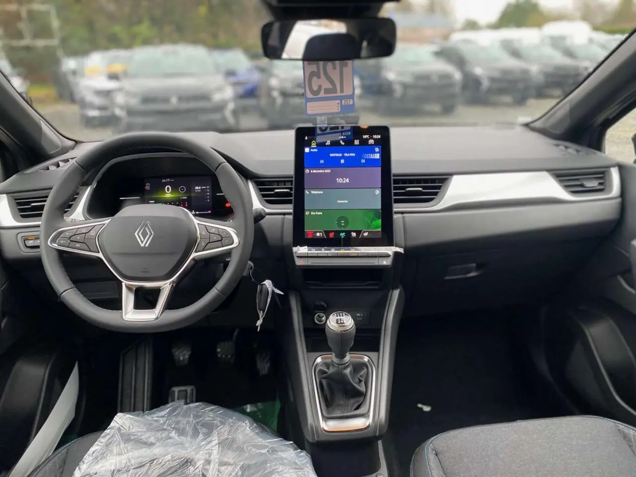 Vue intérieure frontale du tableau de bord du Renault Captur noir étoilé 2025 avec écran tactile vertical et boîte manuelle.