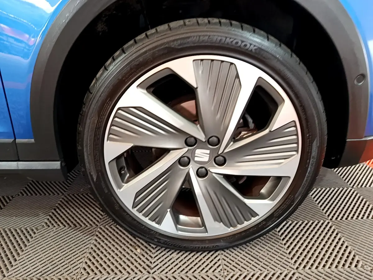 Gros plan sur la jante alliage argentée au design moderne du SEAT Arona bleu, côté roue avant droite.