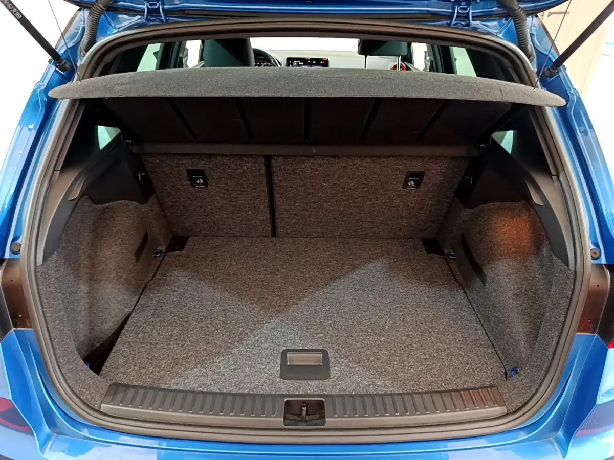 Coffre ouvert vu de l'arrière du SEAT Arona bleu 2022, espace de chargement vide et tapis gris.