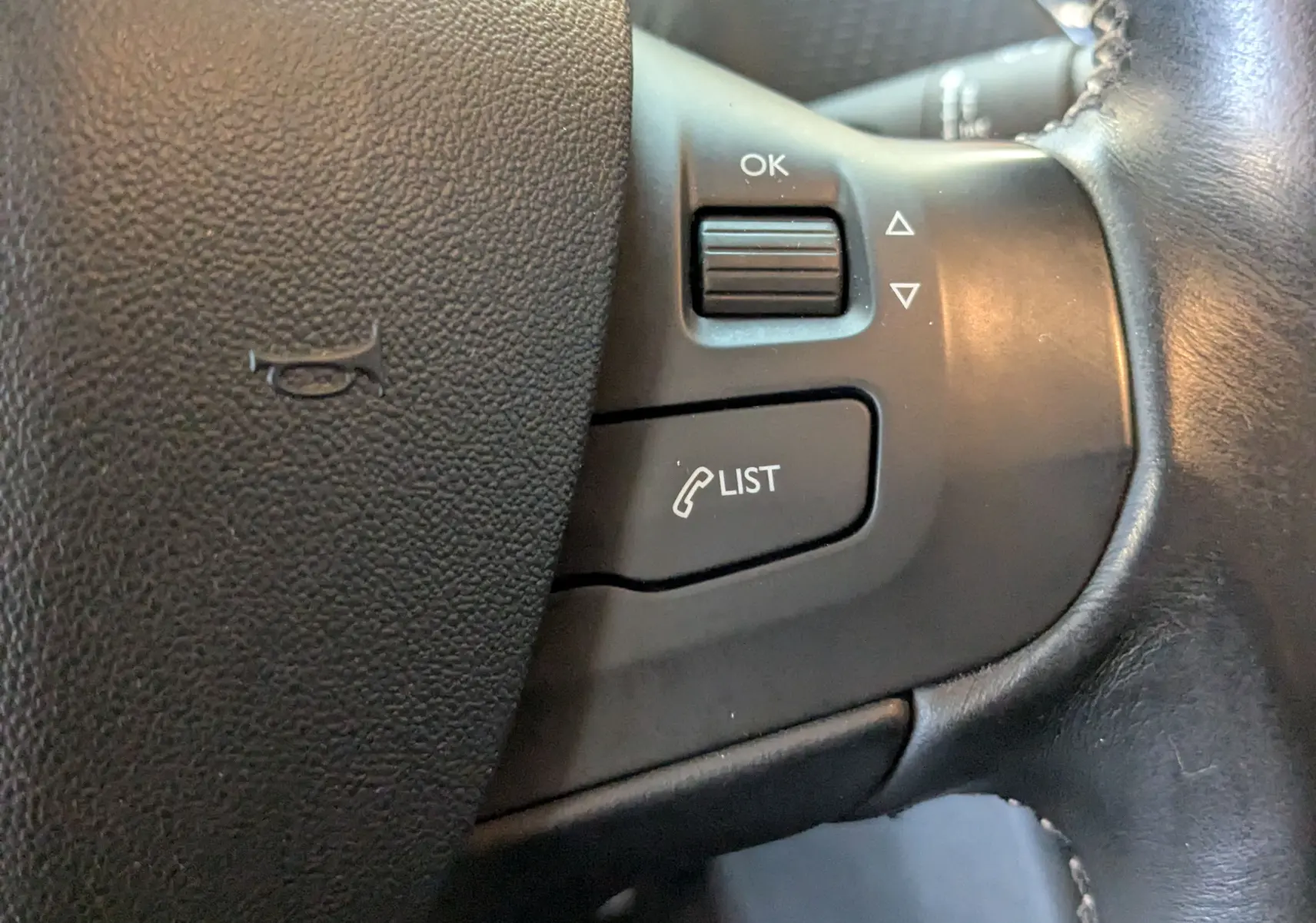 Gros plan sur les commandes du volant en cuir noir d'une Peugeot 2008 blanche, version 1.6 20ch allure de 2017.