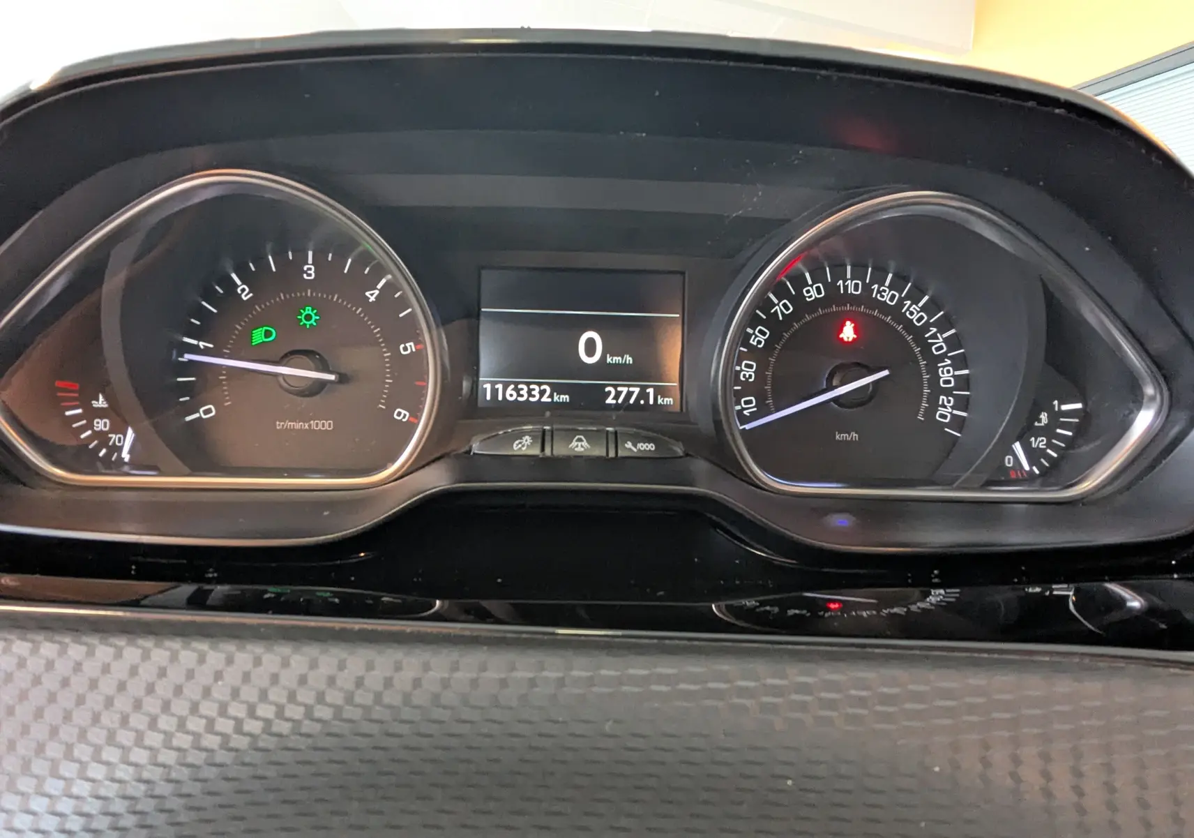 Vue rapprochée du tableau de bord du Peugeot 2008 blanc, affichant le compteur de vitesse et le compte-tours allumés.