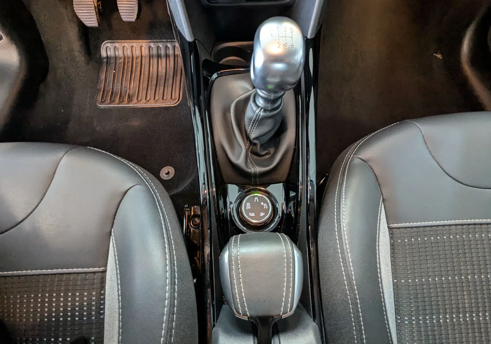 Vue plongeante sur la console centrale de la Peugeot 2008 avec levier de vitesse manuel et sièges noirs en cuir et tissu.