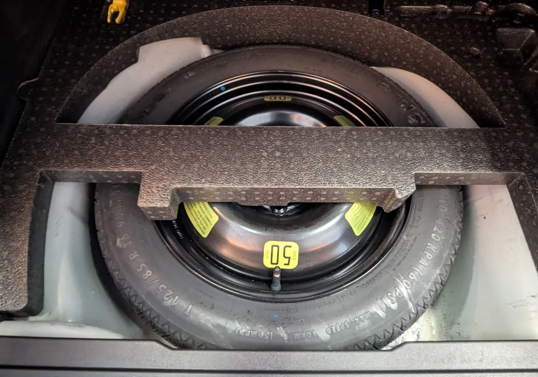 Vue rapprochée de la roue de secours noire dans le coffre d'une Peugeot 2008 blanche de 2017.