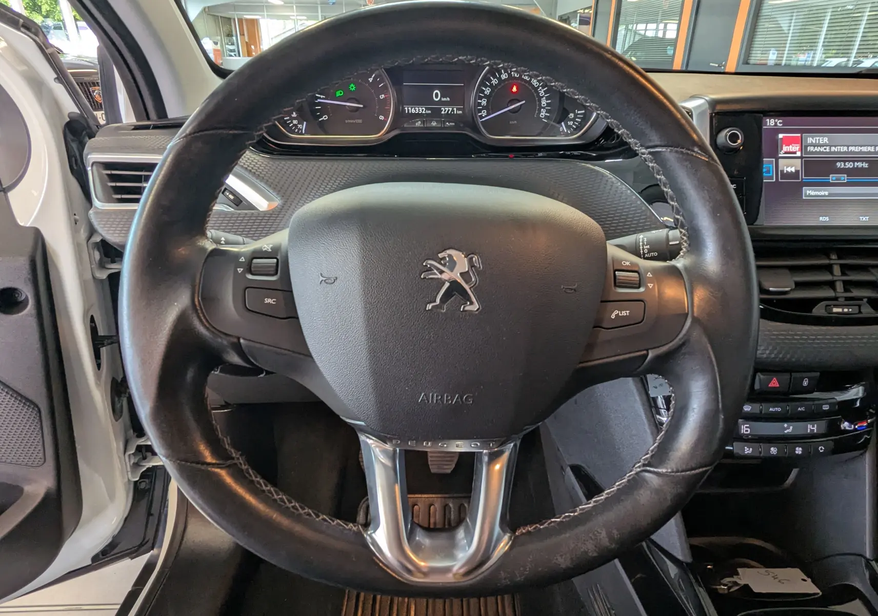 Vue centrée sur le volant en cuir noir du Peugeot 2008 blanc de 2017, avec tableau de bord et écran multimédia visibles.