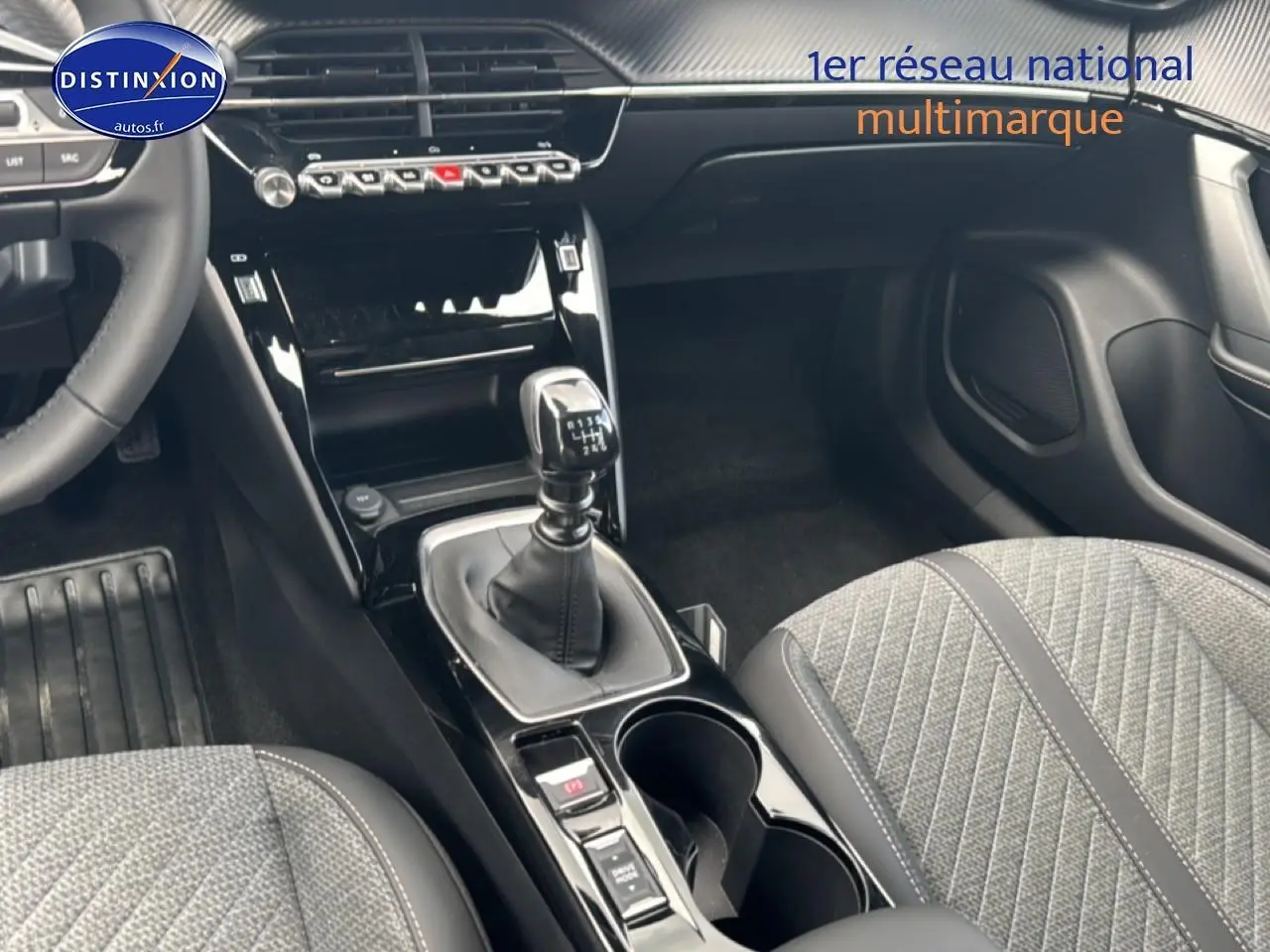 Vue intérieure centrée sur la console centrale et levier de vitesse manuelle, sièges gris tissu embossé dans Peugeot 2008 2025.