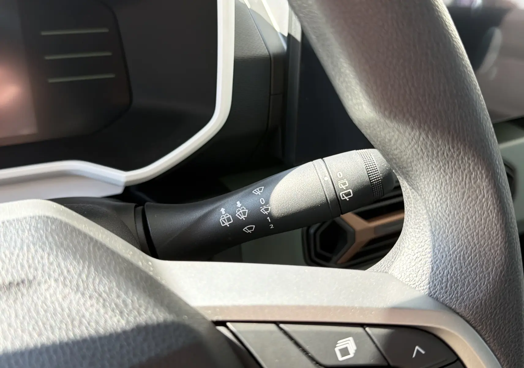 Gros plan sur la commande d’essuie-glace à gauche du volant dans l’habitacle du Dacia Spring 65 Extreme bleu ardoise 2026.