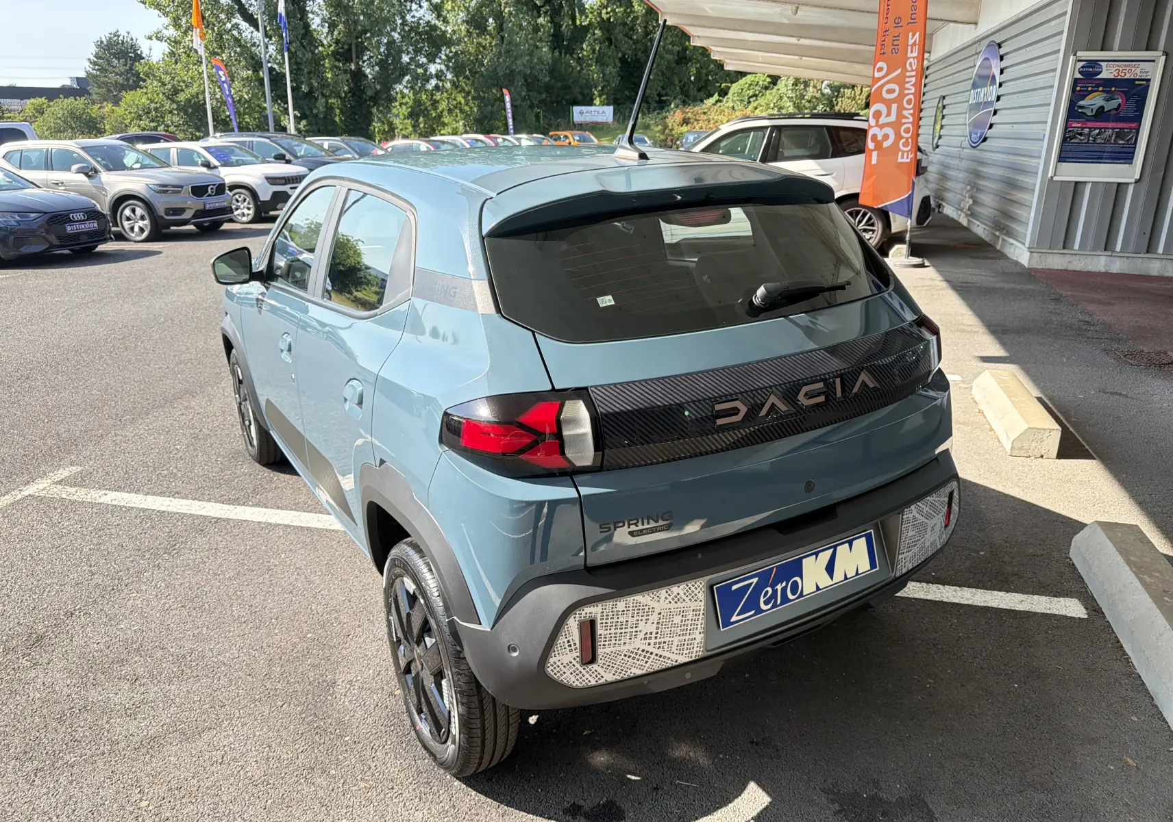 Vue 3/4 arrière d'une Dacia Spring 65 Extreme électrique bleu ardoise avec détails noirs et logo DACIA lumineux.