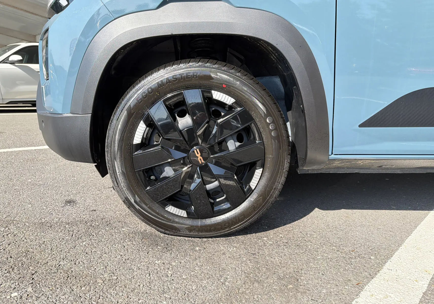 Gros plan sur la roue avant gauche du Dacia Spring 65 Extreme 2026 bleu ardoise, avec jante noire et détails blancs.