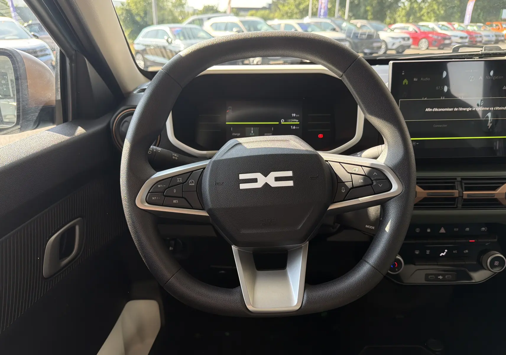 Vue intérieure centrée sur le volant du Dacia Spring 65 Extreme 2026, avec tableau de bord numérique et écran tactile.