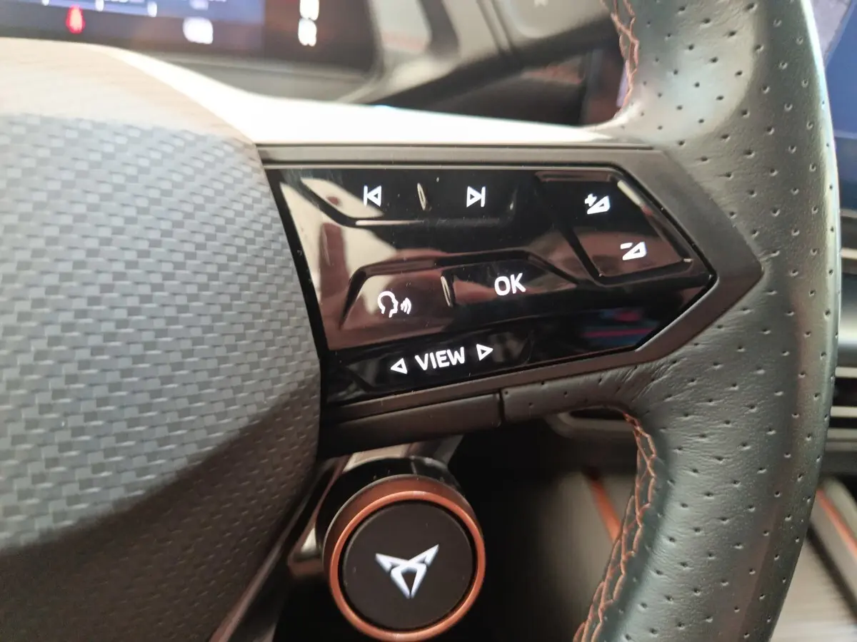 Gros plan sur la partie droite du volant cuir perforé du CUPRA BORN gris foncé, avec commandes tactiles et logo CUPRA central.