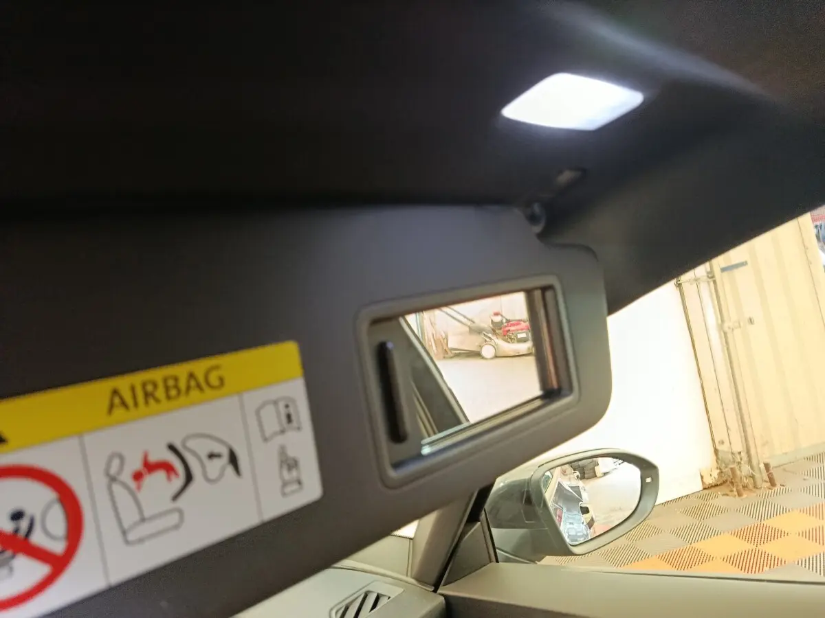 Détail de miroir de courtoisie sur pare-soleil intérieur d’une CUPRA BORN gris foncé, avec rétroviseur latéral visible.