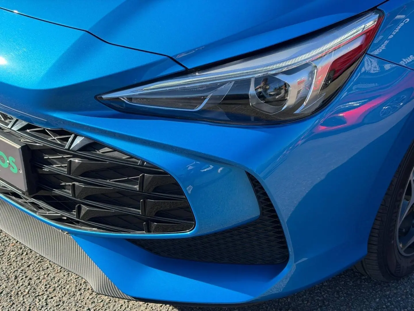 Gros plan sur l'avant droit bleu Como métallisé du MG3 1.5 Hybrid+ 195ch avec phares et calandre distinctifs.