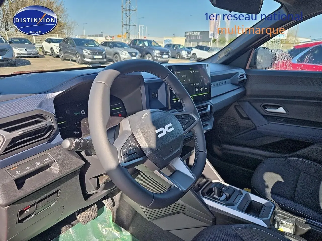 Intérieur du Dacia Duster 2025, vue côté conducteur sur le volant multifonction et l'écran tactile moderne.