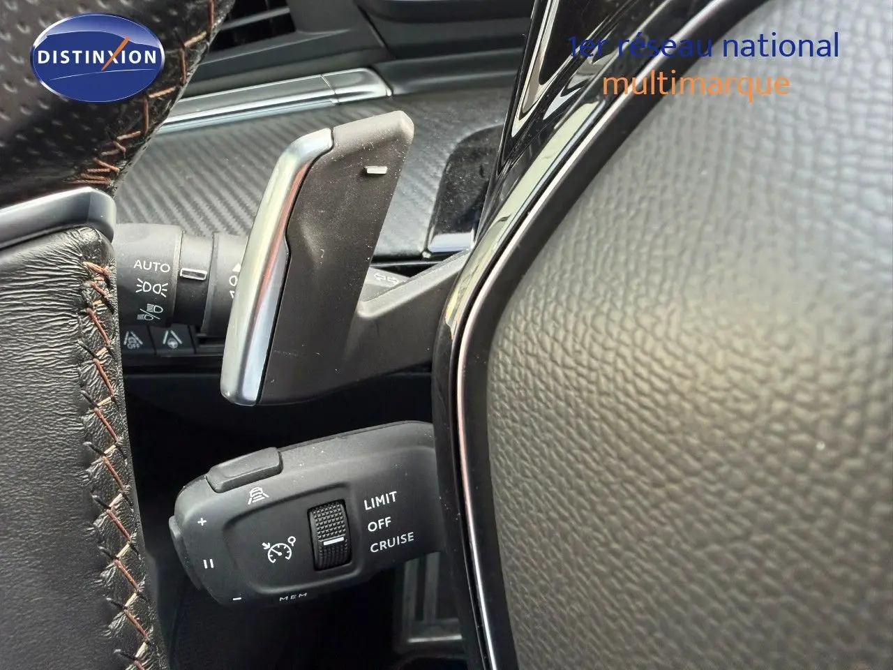 Gros plan sur la commande de régulateur de vitesse et palettes au volant cuir noir sur Peugeot 508 gris platinium.