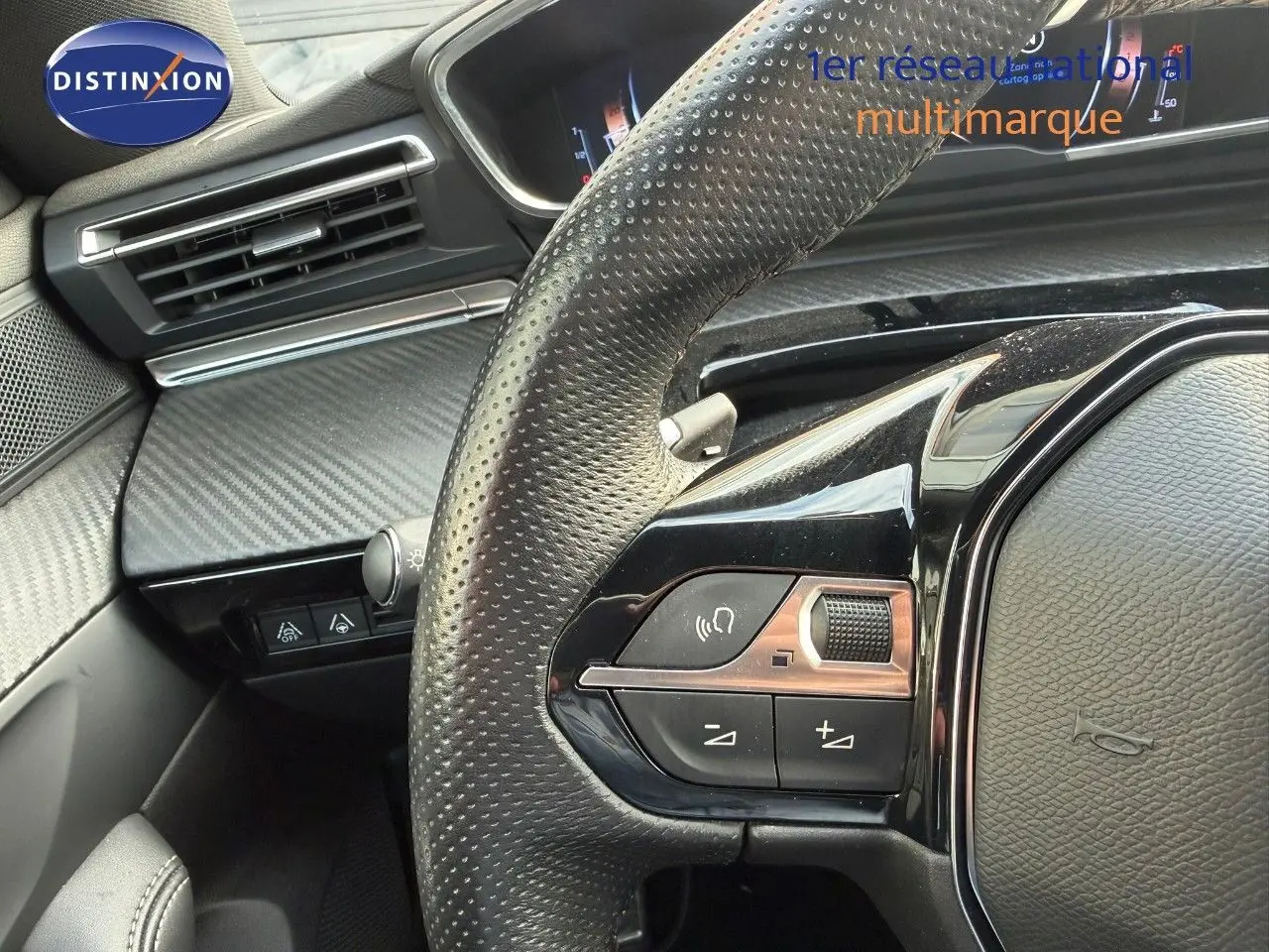 Gros plan sur le volant en cuir perforé côté gauche du Peugeot 508 gris platinium avec commandes audio intégrées.