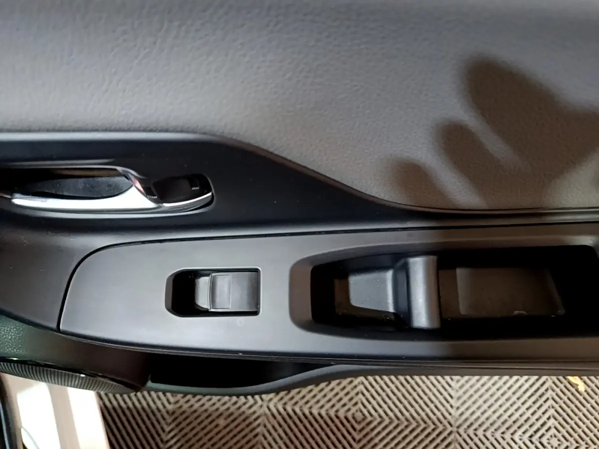 Détail de la commande de lève-vitre côté conducteur sur la porte intérieure noire d'une Toyota Yaris blanche 2020.