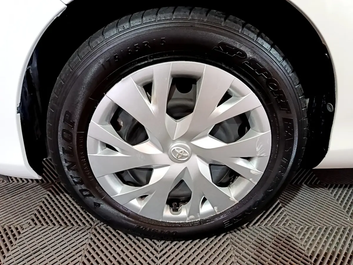 Gros plan sur la roue avant droite blanche d'une Toyota Yaris 1.5 Hybride 2020 avec enjoliveur argenté et logo Toyota central.