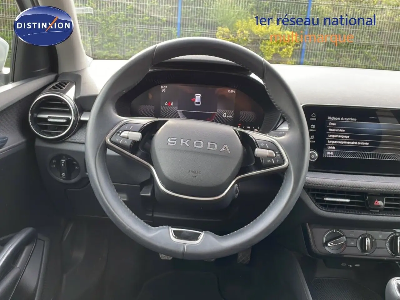 Vue intérieure centrée sur le volant SKODA d'une Fabia blanche glacier, avec tableau de bord numérique et écran tactile.