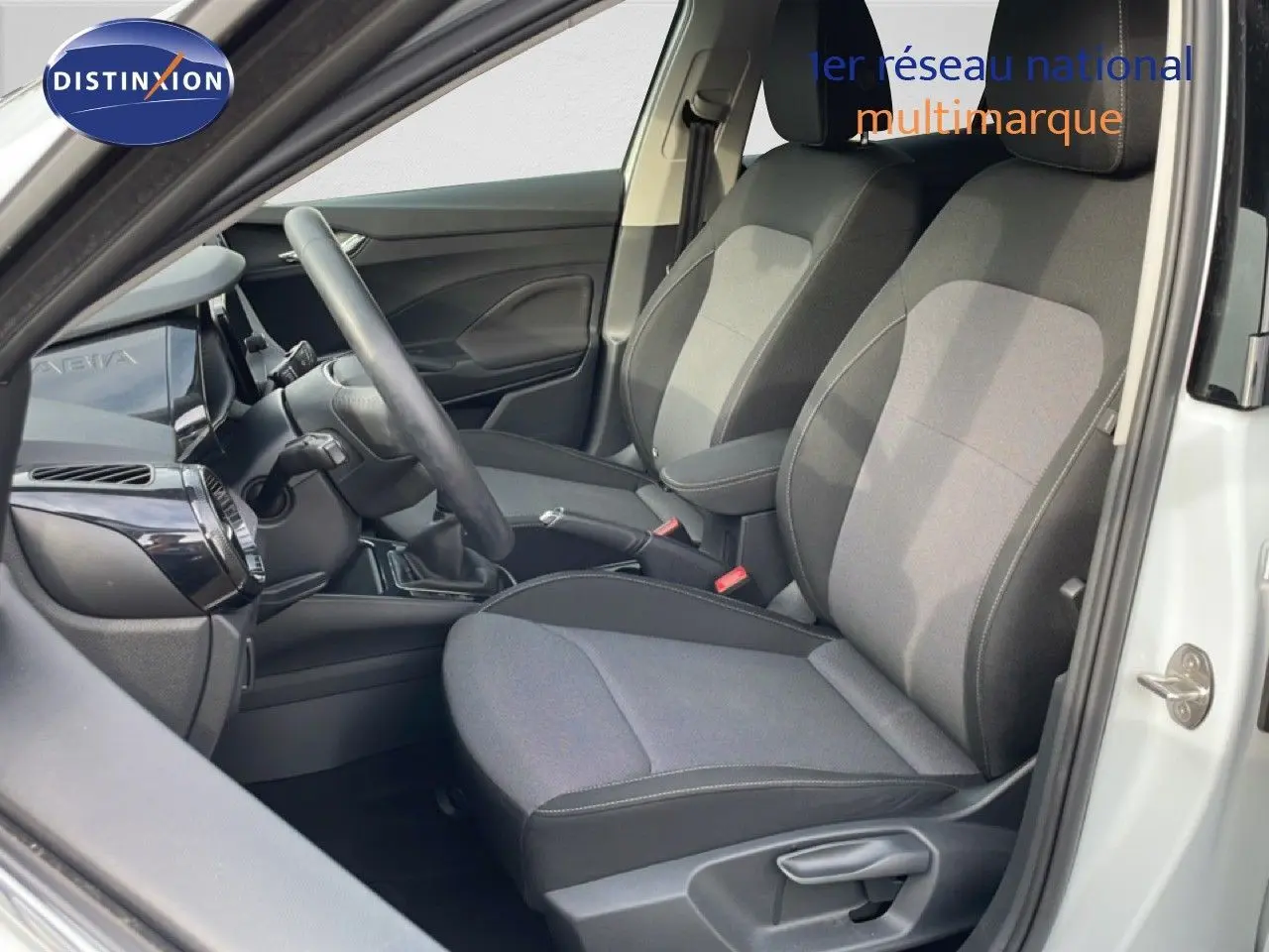 Vue intérieure côté conducteur de la Skoda Fabia blanc glacier 2025, sièges tissu gris et volant multifonction.