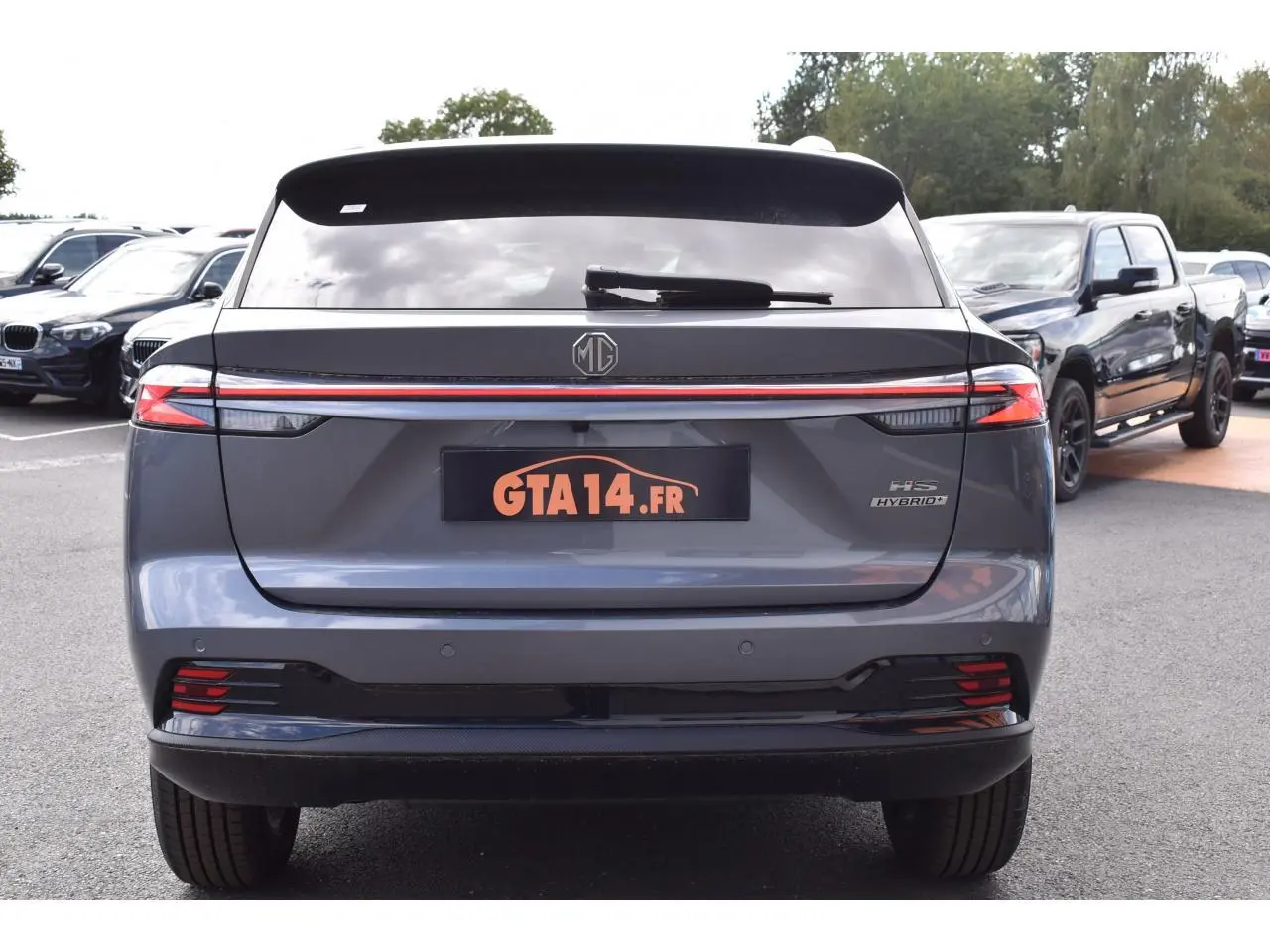 Vue arrière d'un MG Motor EHS gris 2026 avec feux LED reliés par une bande lumineuse rouge et logo MG central.