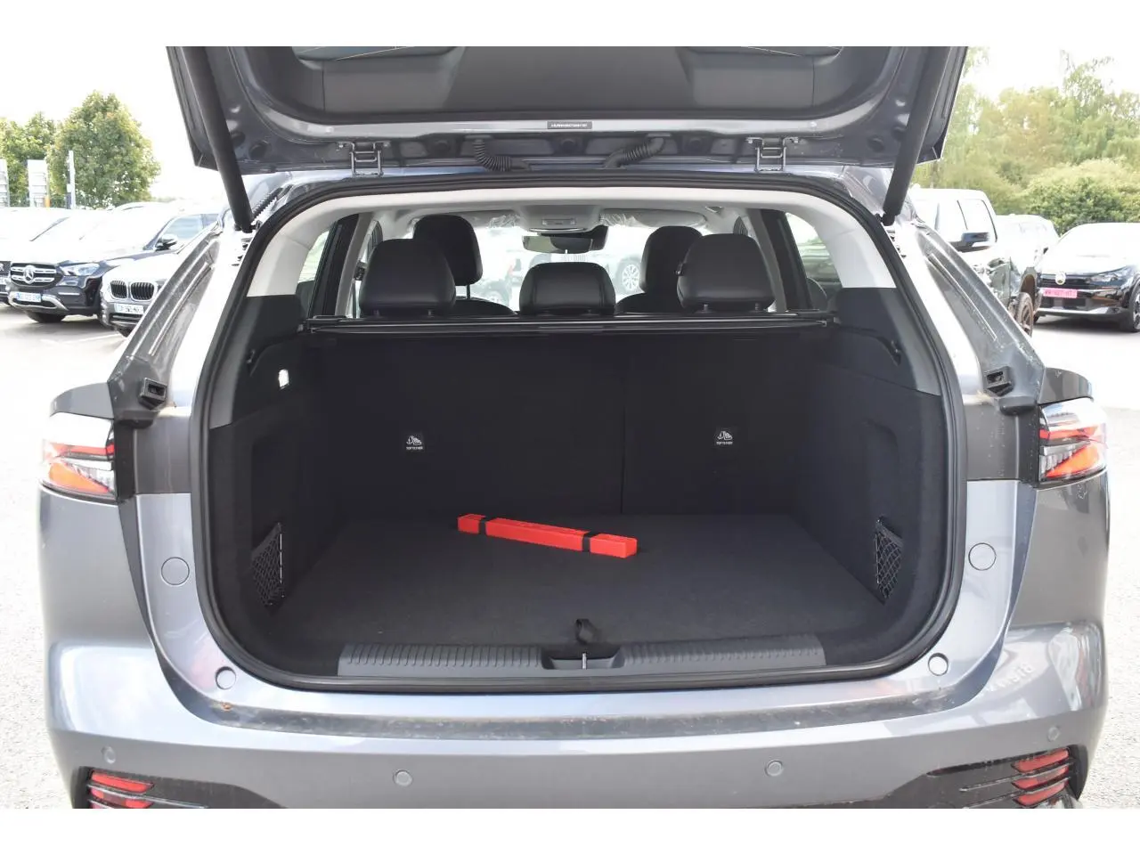 Coffre ouvert vue arrière du MG Motor EHS gris 2026, montrant un espace de chargement vide avec triangle de sécurité rouge.