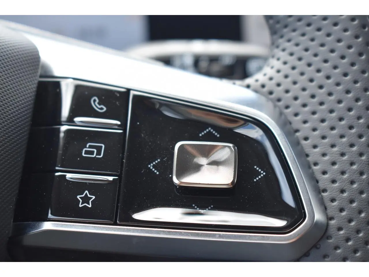 Gros plan sur les commandes multifonctions en plastique noir et chrome du volant perforé du MG Motor EHS gris.