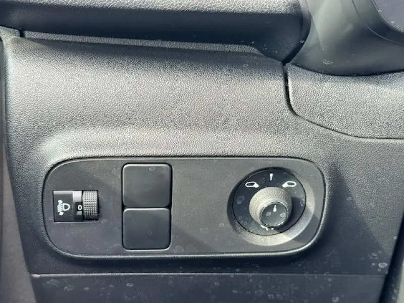 Gros plan sur les commandes de réglage des phares et des rétroviseurs côté gauche d'une Citroën C3 1.2 83ch Shine 2021.