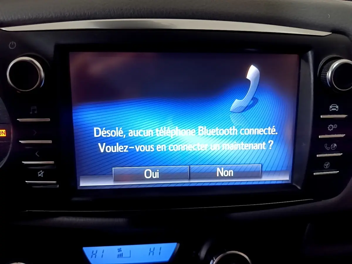 Écran tactile central de la Toyota Yaris hybride 2019 affichant un message Bluetooth, entouré de commandes noires.