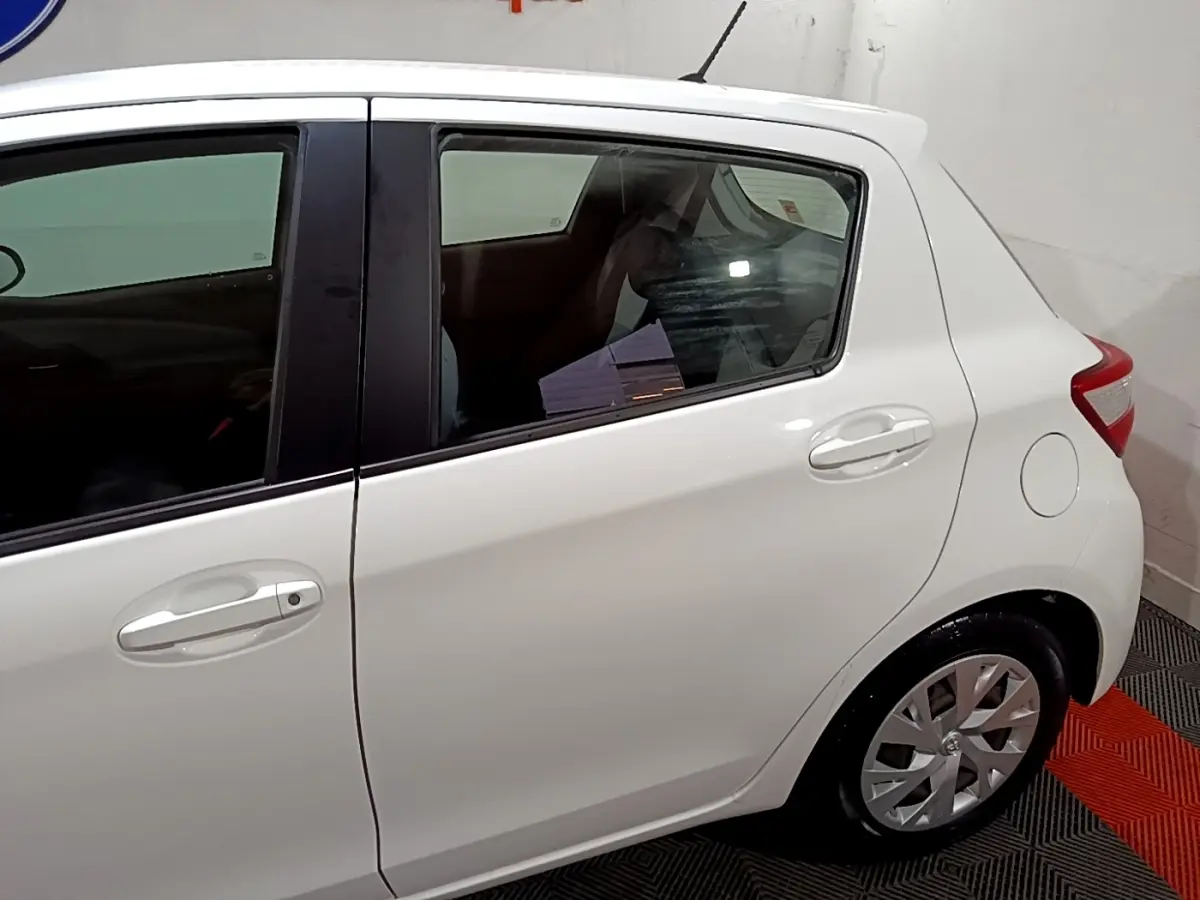Vue latérale droite d'une Toyota Yaris blanche 2019, mettant en valeur les poignées de porte et les jantes en alliage.