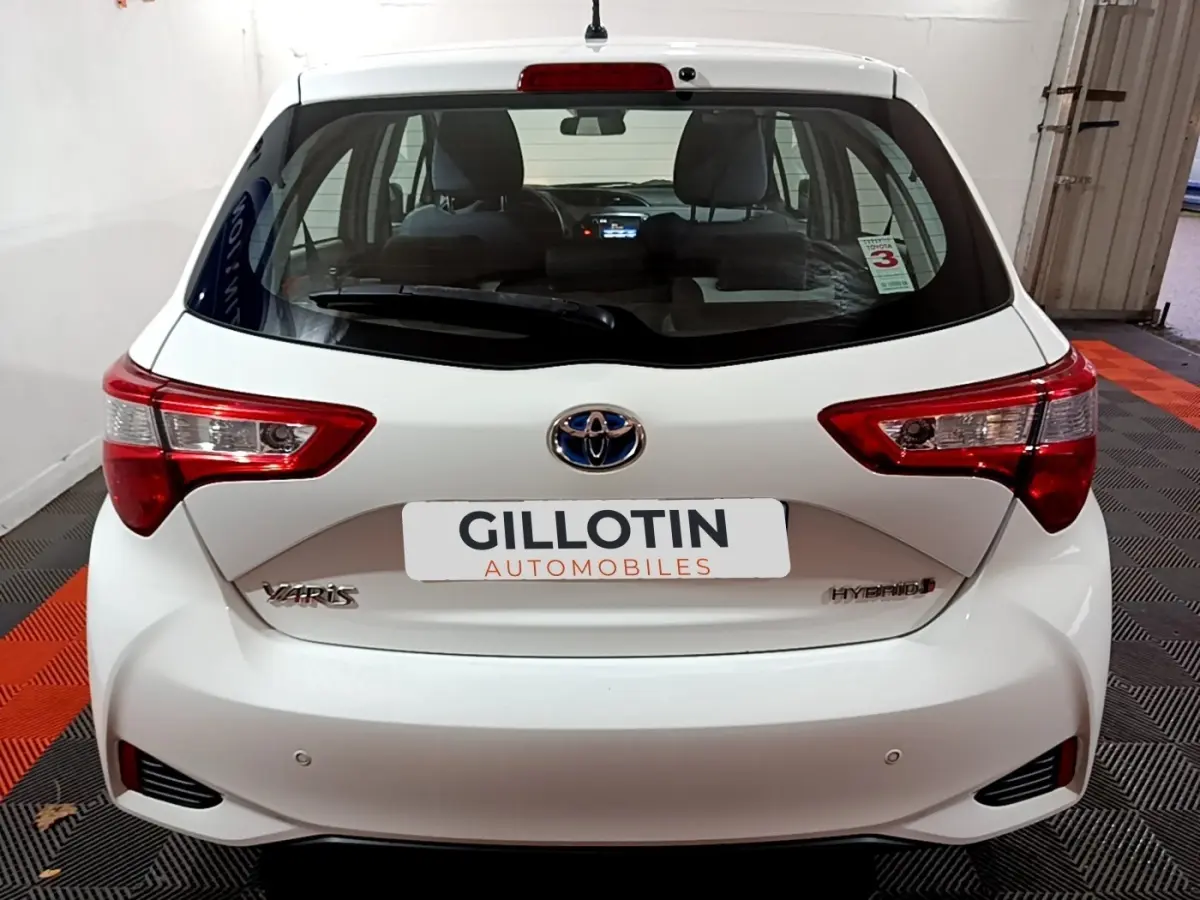 Vue arrière d'une Toyota Yaris blanche hybride 2019 avec feux arrière rouges et logo Toyota centré.