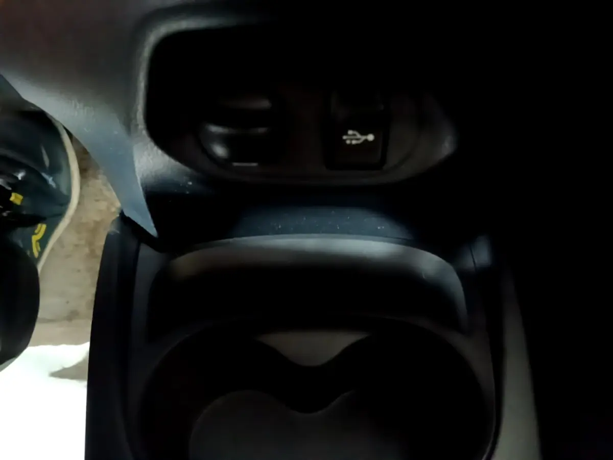 Gros plan sur la console centrale noire de la Toyota Yaris 2019, avec prise USB et porte-gobelets visible.