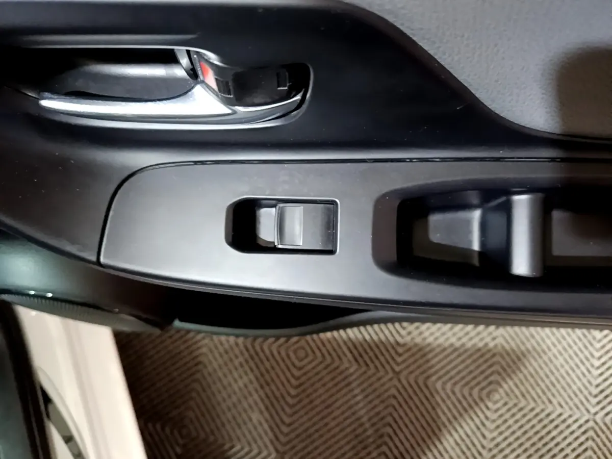 Gros plan sur la commande de lève-vitre côté conducteur de la Toyota Yaris blanche 2019, intérieur noir.